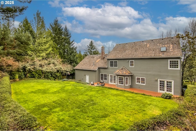 back of property featuring a lawn, french doors, a chimney, and a patio