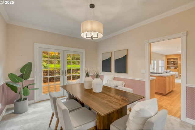 dining space featuring a chandelier, built in features, french doors, and ornamental molding