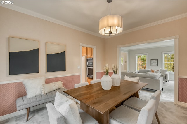 dining space featuring light carpet, a notable chandelier, baseboards, and ornamental molding