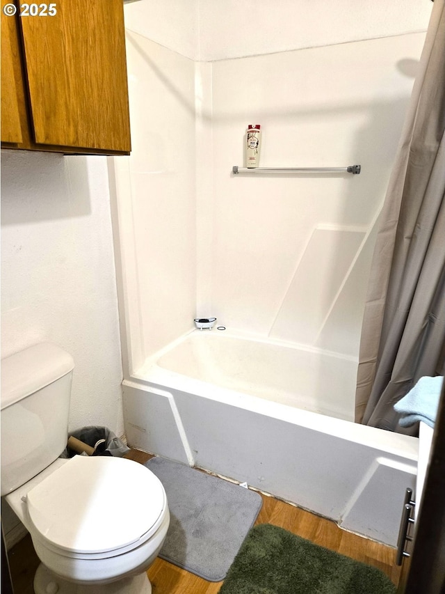 bathroom featuring wood-type flooring, toilet, and shower / bath combo with shower curtain