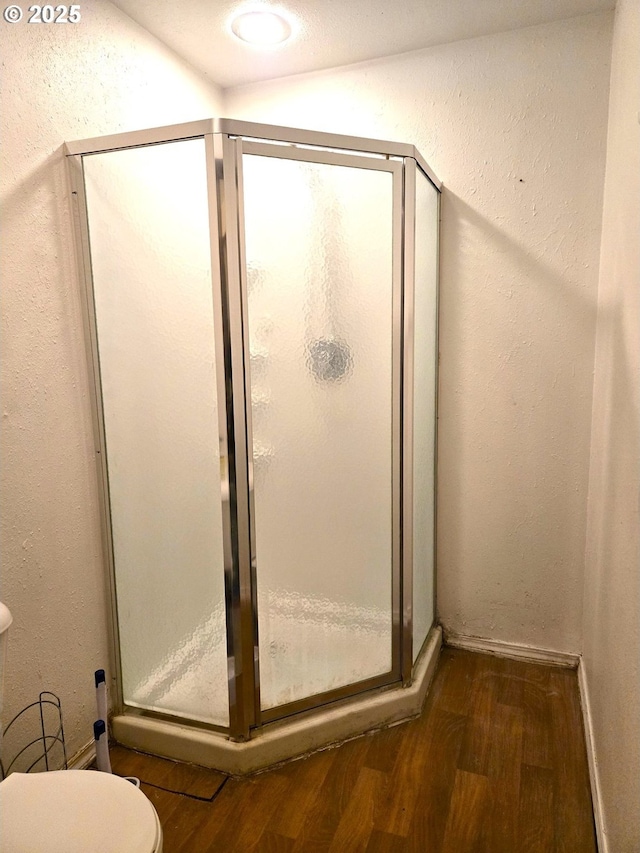 bathroom featuring wood-type flooring, an enclosed shower, and toilet