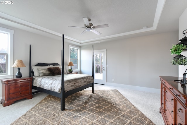 bedroom with baseboards, light colored carpet, ceiling fan, access to exterior, and a tray ceiling