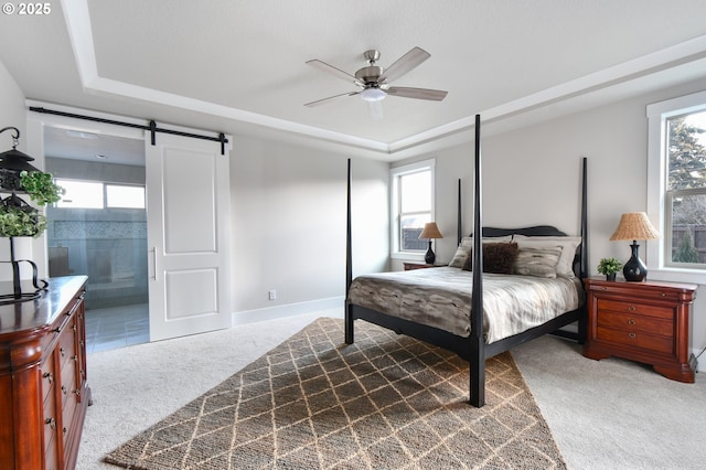 bedroom with a barn door, baseboards, a raised ceiling, ceiling fan, and carpet floors