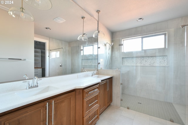 bathroom featuring a stall shower, a walk in closet, a sink, and double vanity