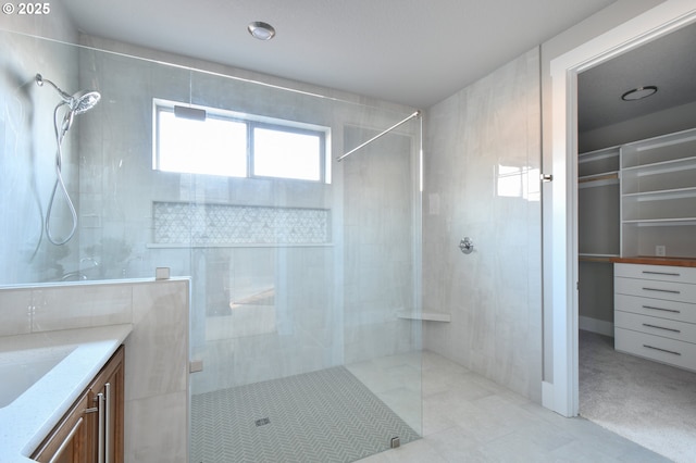 bathroom featuring walk in shower, vanity, and a walk in closet