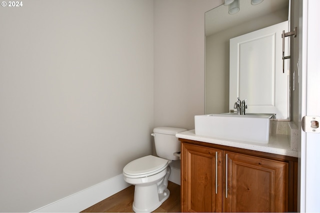 bathroom with toilet, baseboards, wood finished floors, and vanity