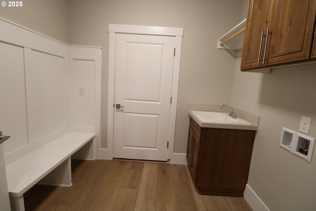 washroom with hookup for a washing machine, cabinet space, a sink, light wood-type flooring, and baseboards