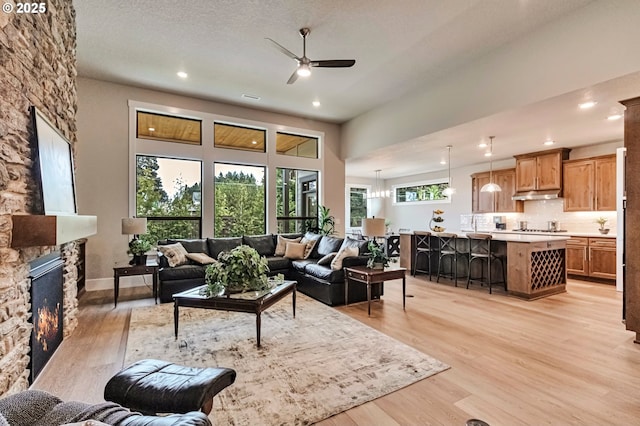 4909 NE 132nd Cir, Vancouver, WA 98686 - living room featuring ceiling fan, a stone fireplace, light wood finished floors, recessed lighting, and a towering ceiling