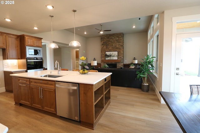 kitchen with a kitchen island with sink, built in microwave, light countertops, stainless steel dishwasher, and black oven