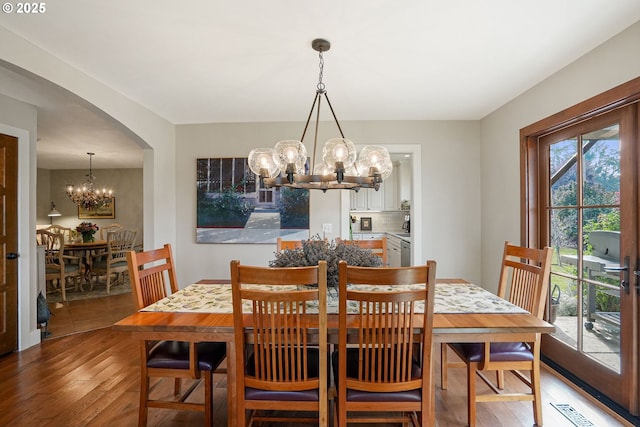 dining room featuring wood-type flooring and an inviting chandelier