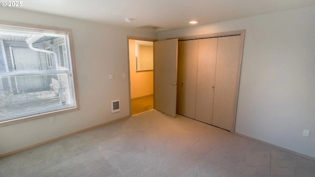 unfurnished bedroom featuring light colored carpet and a closet