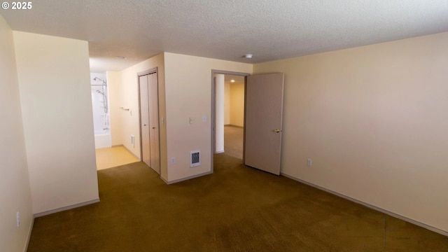 spare room with a textured ceiling and dark colored carpet