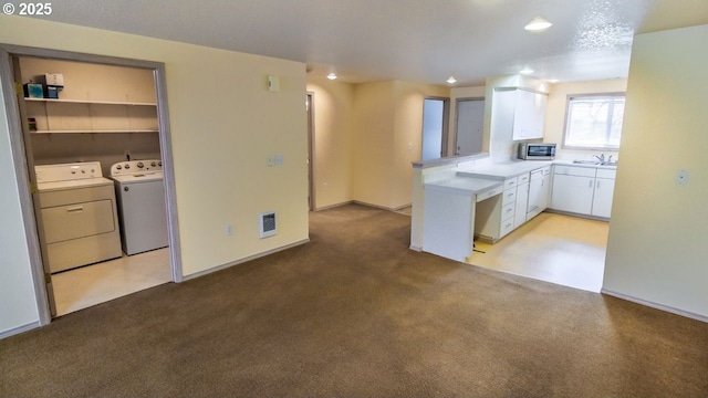 kitchen with white cabinetry, sink, light colored carpet, and washing machine and clothes dryer