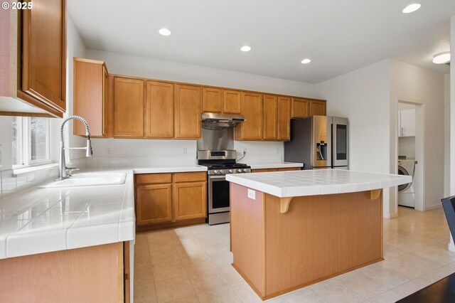 15820 SW Towhee Ln, Beaverton, OR 97007 - kitchen featuring stainless steel appliances, a sink, tile countertops, under cabinet range hood, and light tile patterned floors