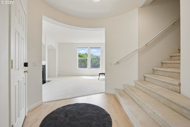 15820 SW Towhee Ln, Beaverton, OR 97007 - carpeted entryway with wood finished floors, stairs, a fireplace with flush hearth, and arched walkways