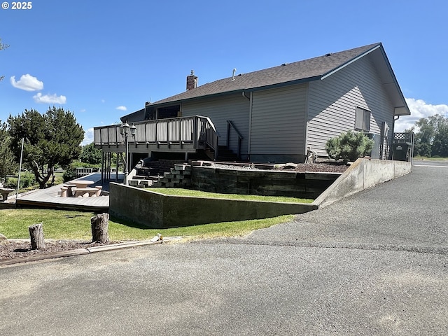 29843 Royce Ln, Hermiston, OR 97838 - view of home's exterior with a wooden deck, a chimney, stairs, roof with shingles, and a lawn