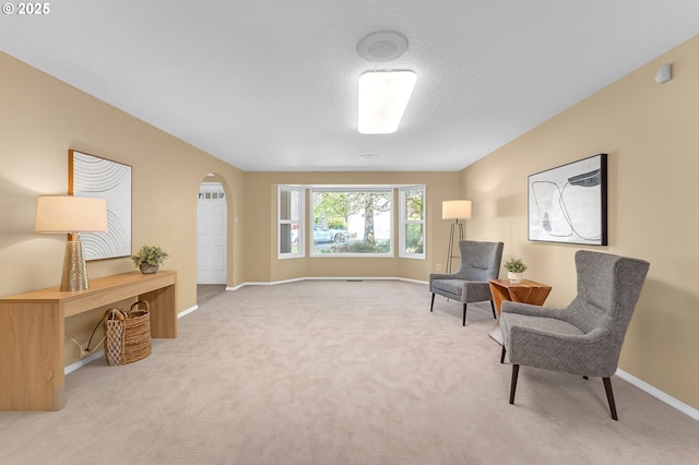 living area featuring carpet, baseboards, and arched walkways