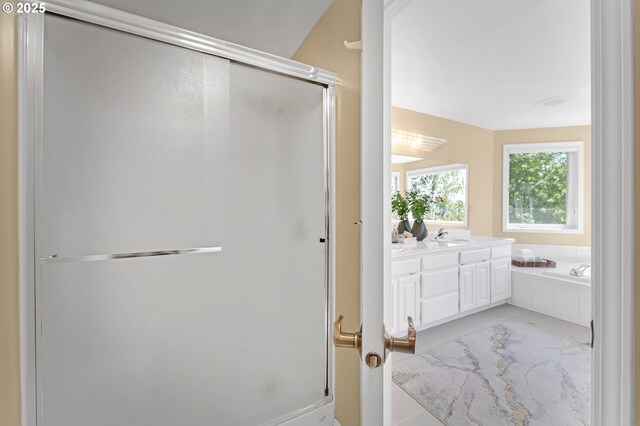 full bathroom featuring a stall shower, a bath, and vanity