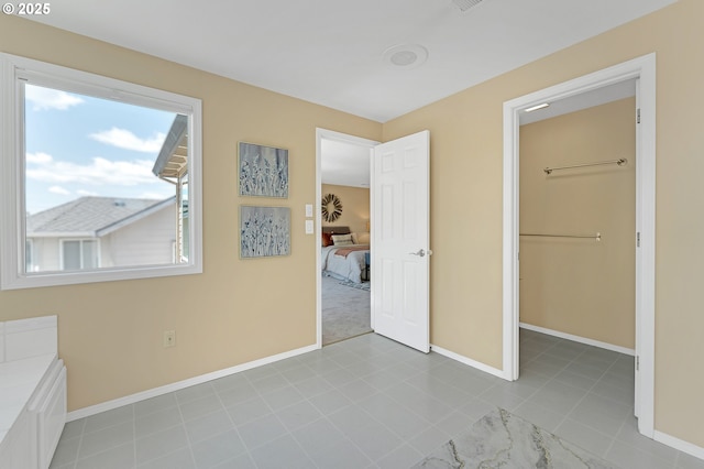 unfurnished bedroom with baseboards and a walk in closet