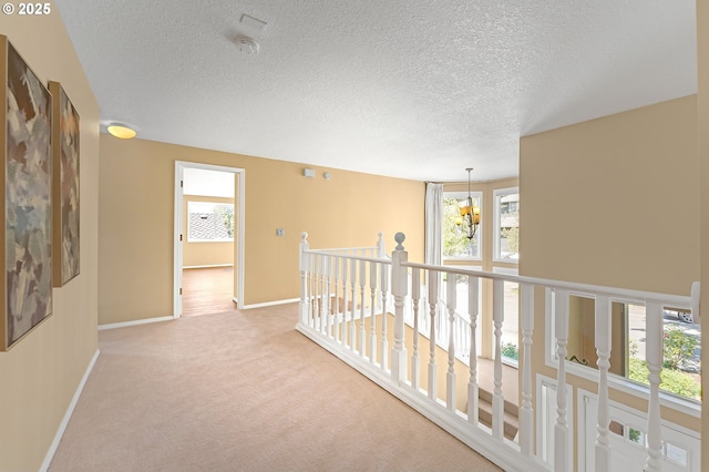 13055 Princeton Ct, Lake Oswego, OR 97035 - corridor featuring baseboards, light colored carpet, a chandelier, an upstairs landing, and a textured ceiling