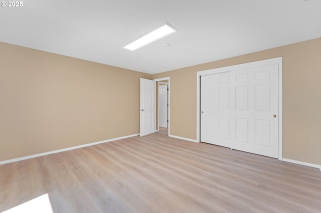 unfurnished bedroom with light wood-type flooring, baseboards, and a closet