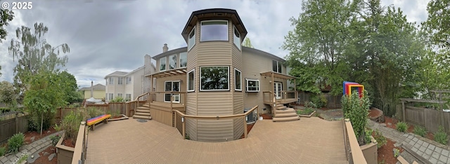 rear view of property featuring fence and a wooden deck