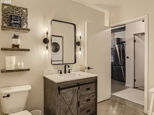 1030 NW 12th Ave Unit 410, Portland, OR 97209 - bathroom with concrete floors, vanity, stacked washer and dryer, and toilet