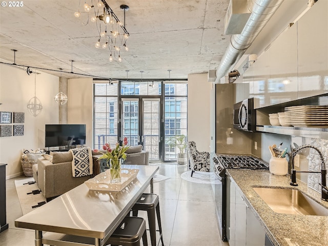 1030 NW 12th Ave Unit 410, Portland, OR 97209 - kitchen with floor to ceiling windows, a sink, stainless steel microwave, light stone counters, and gas range oven