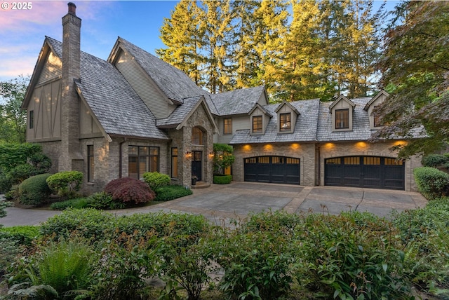 view of front of home featuring a chimney, concrete driveway, a high end roof, stone siding, and brick siding