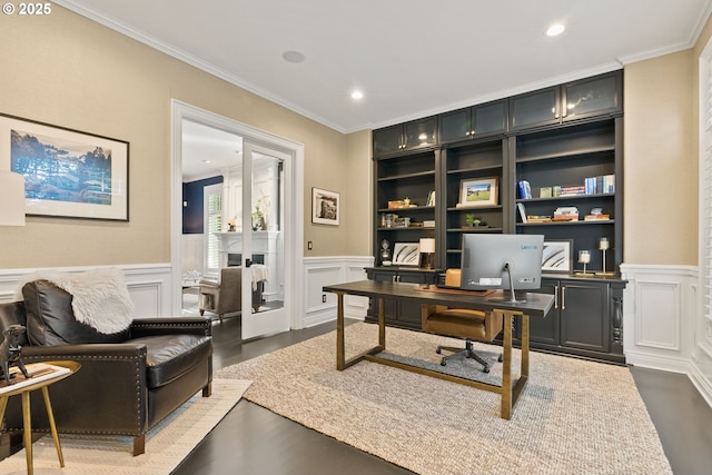 office area with crown molding, a decorative wall, a wainscoted wall, and dark wood-style flooring