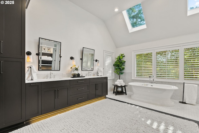 full bathroom with high vaulted ceiling, a skylight, a freestanding tub, and double vanity