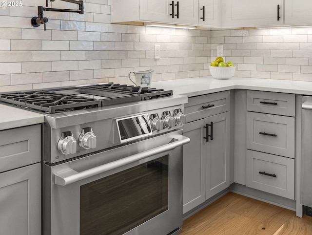 90202 Hobie Rd, Warrenton, OR 97146 - kitchen featuring stainless steel range, gray cabinetry, light countertops, light wood finished floors, and tasteful backsplash