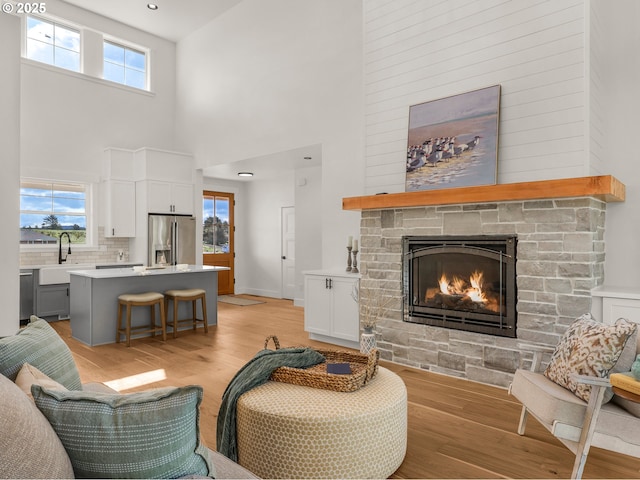 90202 Hobie Rd, Warrenton, OR 97146 - living room with a towering ceiling, a stone fireplace, light wood-style flooring, and plenty of natural light