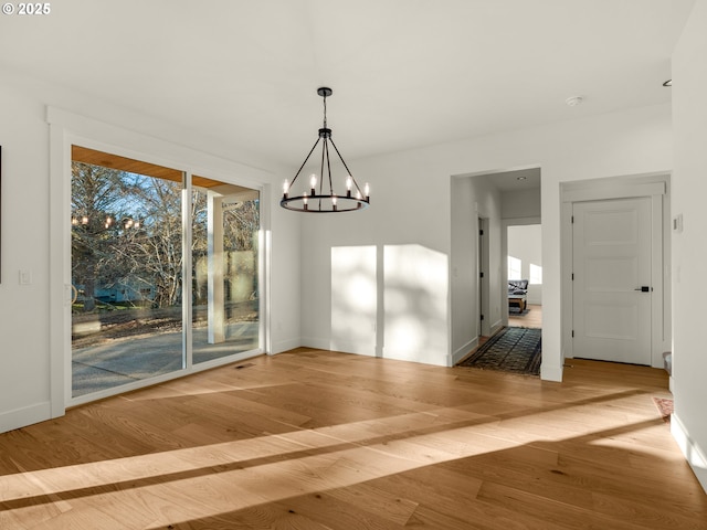 unfurnished dining area featuring hardwood / wood-style floors and a chandelier