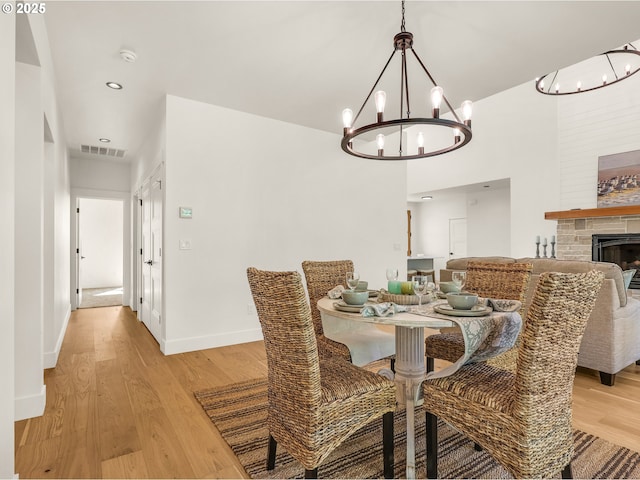 90202 Hobie Rd, Warrenton, OR 97146 - dining area featuring a chandelier, light wood-style floors, baseboards, recessed lighting, and a stone fireplace