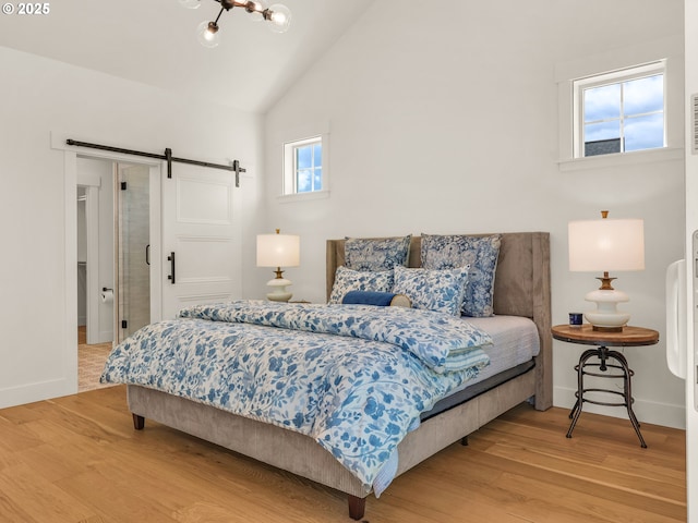 90202 Hobie Rd, Warrenton, OR 97146 - bedroom with a barn door, light wood finished floors, baseboards, high vaulted ceiling, and a chandelier