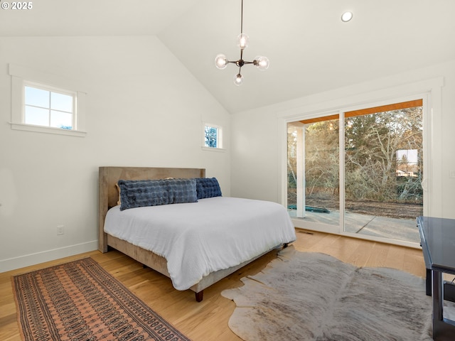 bedroom with hardwood / wood-style floors, lofted ceiling, access to outside, and an inviting chandelier