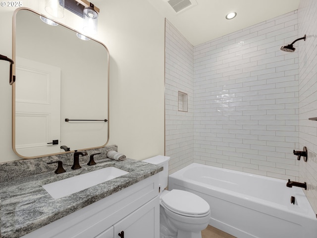 full bathroom featuring tiled shower / bath, vanity, and toilet