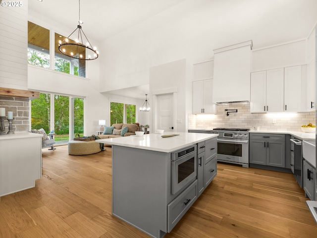 90202 Hobie Rd, Warrenton, OR 97146 - kitchen with gray cabinets, stainless steel appliances, a chandelier, a towering ceiling, and tasteful backsplash