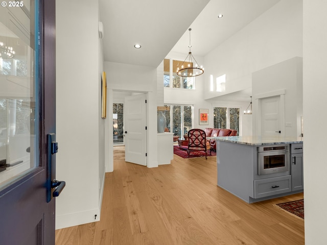 entryway with a high ceiling, an inviting chandelier, and light hardwood / wood-style flooring