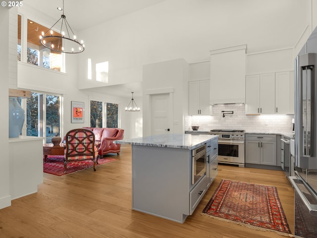 kitchen featuring an inviting chandelier, gray cabinets, a center island, and high quality appliances