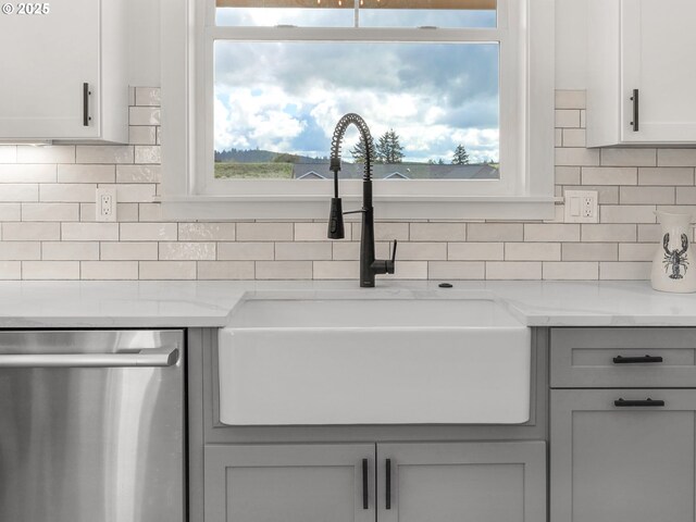 90202 Hobie Rd, Warrenton, OR 97146 - kitchen view of stainless steel dishwasher, a sink, gray cabinetry, backsplash, and light stone counters