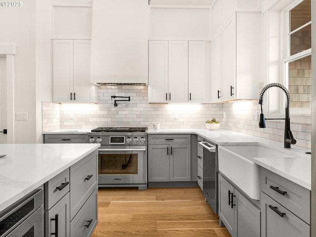 90202 Hobie Rd, Warrenton, OR 97146 - kitchen with appliances with stainless steel finishes, gray cabinetry, a sink, light stone countertops, and tasteful backsplash