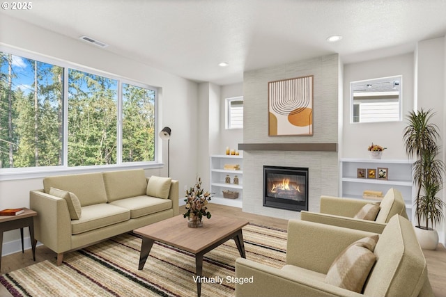 7827 SW Thornbridge Ter Unit 9, Beaverton, OR 97007 - living room featuring a tiled fireplace, wood finished floors, recessed lighting, and built in features