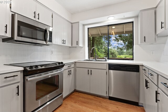 13980 Shireva Ct, Lake Oswego, OR 97034 - kitchen featuring appliances with stainless steel finishes, light countertops, decorative backsplash, and light wood-type flooring