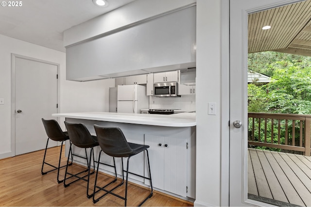 13980 Shireva Ct, Lake Oswego, OR 97034 - kitchen with appliances with stainless steel finishes, a peninsula, light countertops, white cabinets, and a kitchen breakfast bar