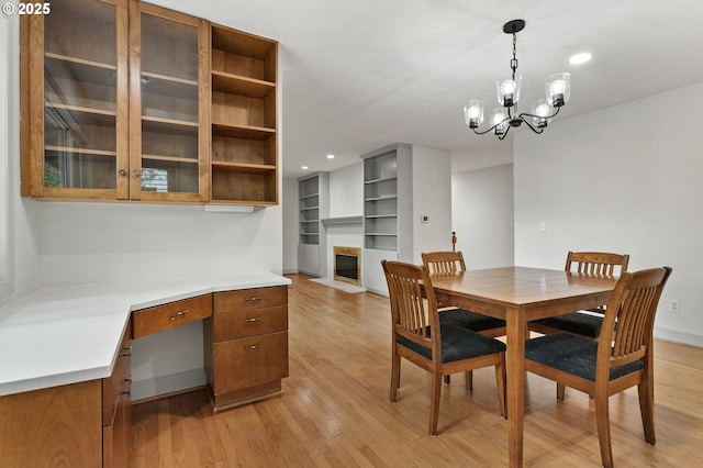 13980 Shireva Ct, Lake Oswego, OR 97034 - dining area featuring light wood-style floors, a fireplace with flush hearth, recessed lighting, a chandelier, and built in desk