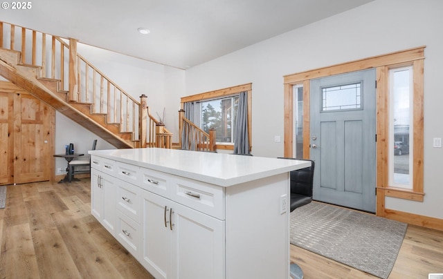 kitchen with a kitchen island, white cabinetry, baseboards, light countertops, and light wood finished floors