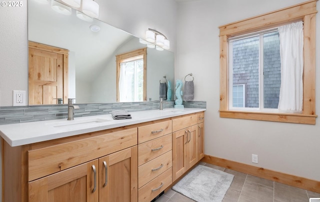 full bath featuring double vanity, tasteful backsplash, baseboards, vaulted ceiling, and a sink