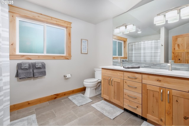 bathroom with curtained shower, toilet, a sink, baseboards, and double vanity